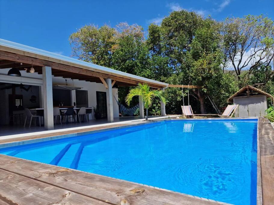 uma grande piscina com um deque de madeira e uma casa em Kazacactus-villa 3 chambres piscine Marie-Galante em Beauséjour