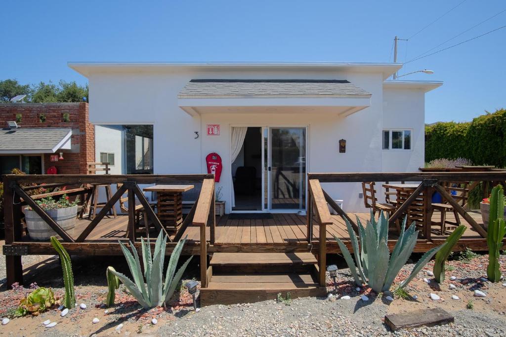 ein kleines weißes Haus mit einer Holzterrasse in der Unterkunft Casa de Sara in Villa de Juárez