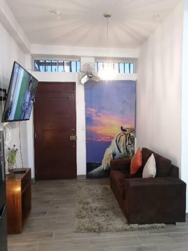 a living room with a couch and a painting of a tiger at Departamento in Pucallpa