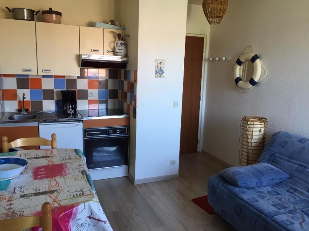 Il comprend une cuisine et un salon avec un canapé bleu. dans l'établissement Appartement 2 pièces au calme avec balcon, parking, à 500m de la plage - Villers-sur-Mer - FR-1-712-21, à Villers-sur-Mer