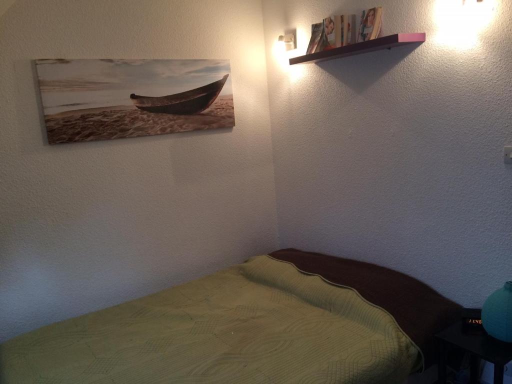 a bedroom with a bed and a picture of a boat on the wall at Appartement Villers-sur-Mer, 2 pièces, 4 personnes - FR-1-712-24 in Villers-sur-Mer