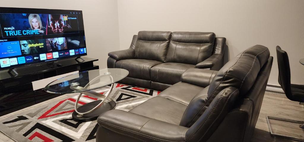 a living room with two leather chairs and a flat screen tv at ChessKings Executive Suite - 2 Bedrooms in Winnipeg