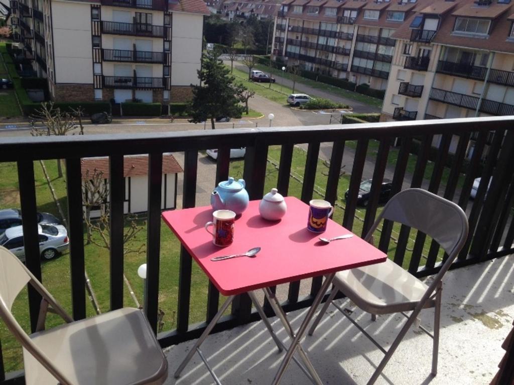 une table et des chaises roses sur un balcon avec deux tasses dans l'établissement Appartement 2 Pièces avec Balcon Sud à 50m de la Plage, Parking Privatif - Villers-sur-Mer - FR-1-712-15, à Villers-sur-Mer