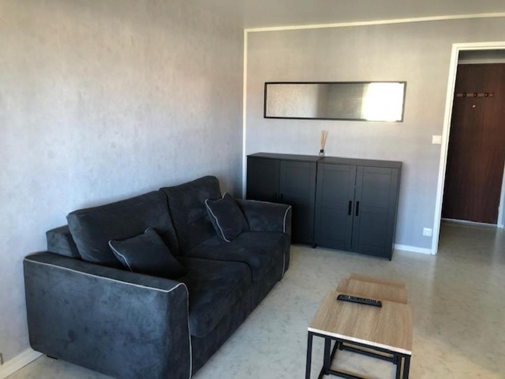 un salon avec un canapé noir et une table dans l'établissement Appartement charmant proche plage et commerces - FR-1-712-13, à Villers-sur-Mer