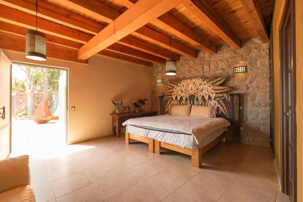 sypialnia z łóżkiem i kamienną ścianą w obiekcie Casa de campo nubes cerca de Morelia w mieście Patámbaro