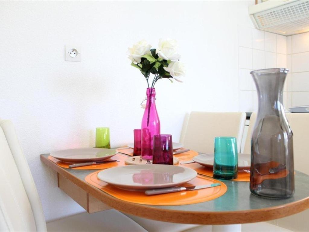 a table with a vase and plates and flowers on it at Appartement La Rochelle, 2 pièces, 4 personnes - FR-1-246-648 in La Rochelle