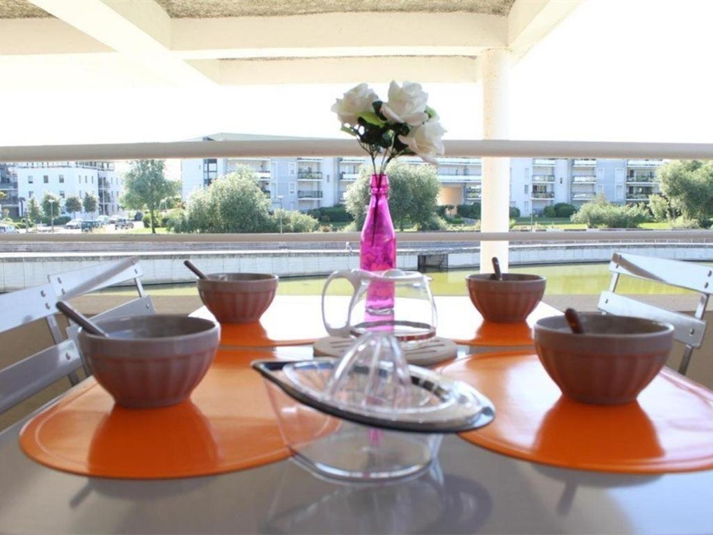a table with bowls and a vase with flowers on it at Appartement La Rochelle, 2 pièces, 4 personnes - FR-1-246-648 in La Rochelle