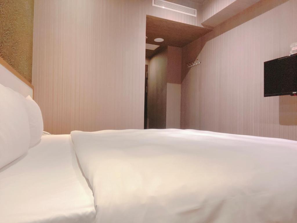 a white bed in a room with a flat screen tv at Centre Hotel in Kaohsiung