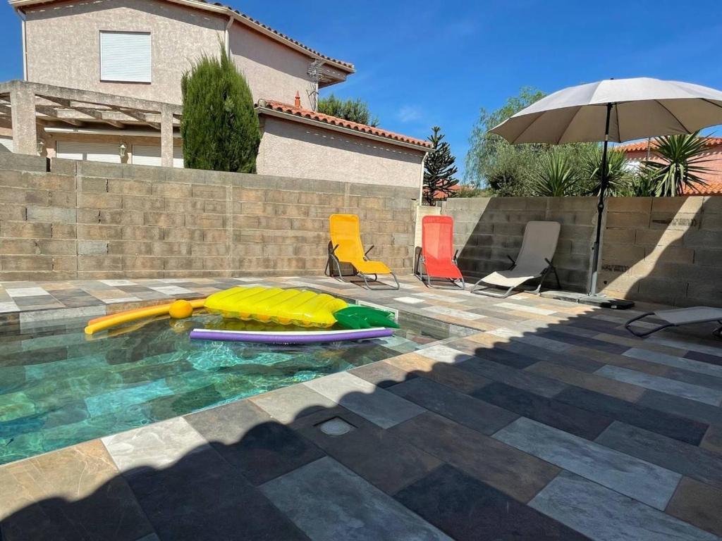 a pool with a pool noodle and chairs and an umbrella at Maison- Elne (66) - FR-1-225-772 in Elne