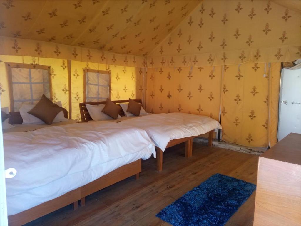 a bedroom with two beds in a room with yellow walls at Nitya Village Retreat in Chamba