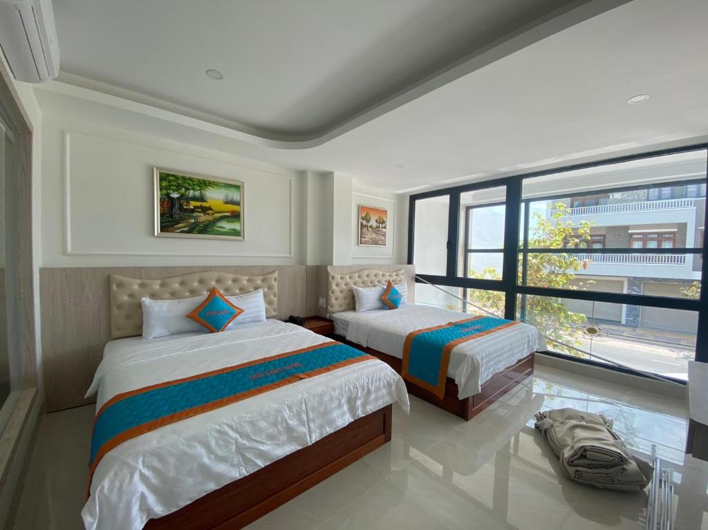 sypialnia z 2 łóżkami i dużym oknem w obiekcie KHÁCH SẠN Biển Xanh w mieście Kinh Dinh