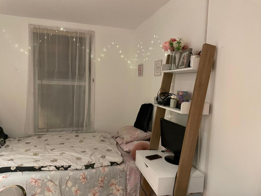 a bedroom with a bed and a desk with a television at Studio flat in Stratford in London