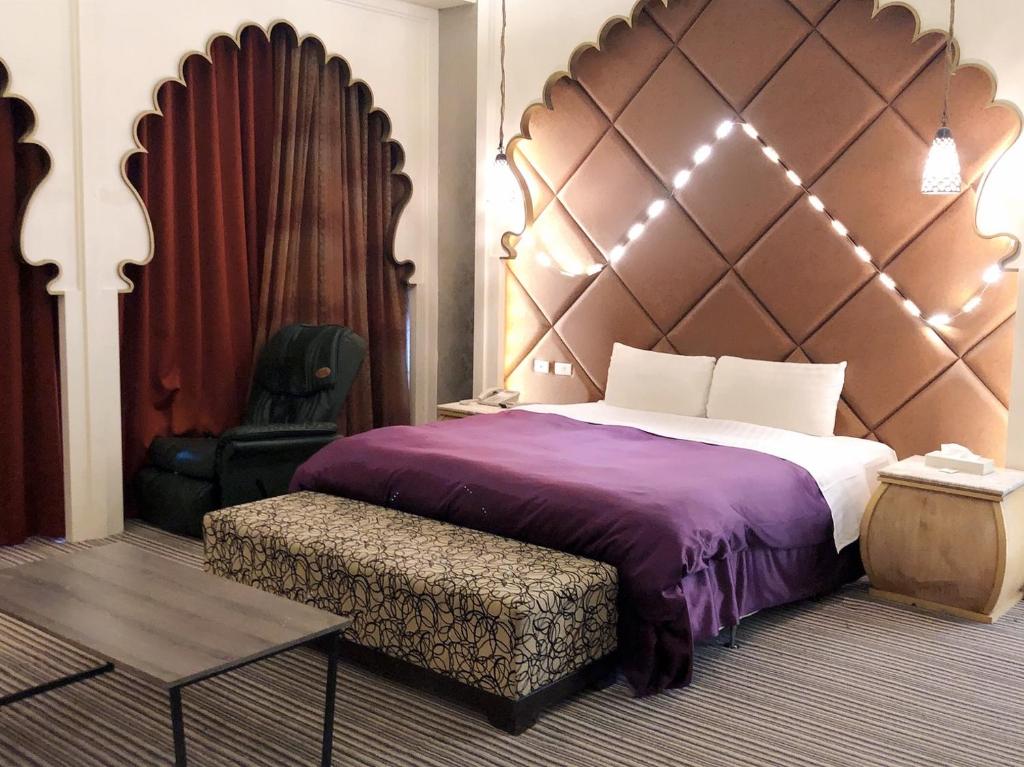 een slaapkamer met een groot bed en een stoel bij Idee Motel in Changhua City