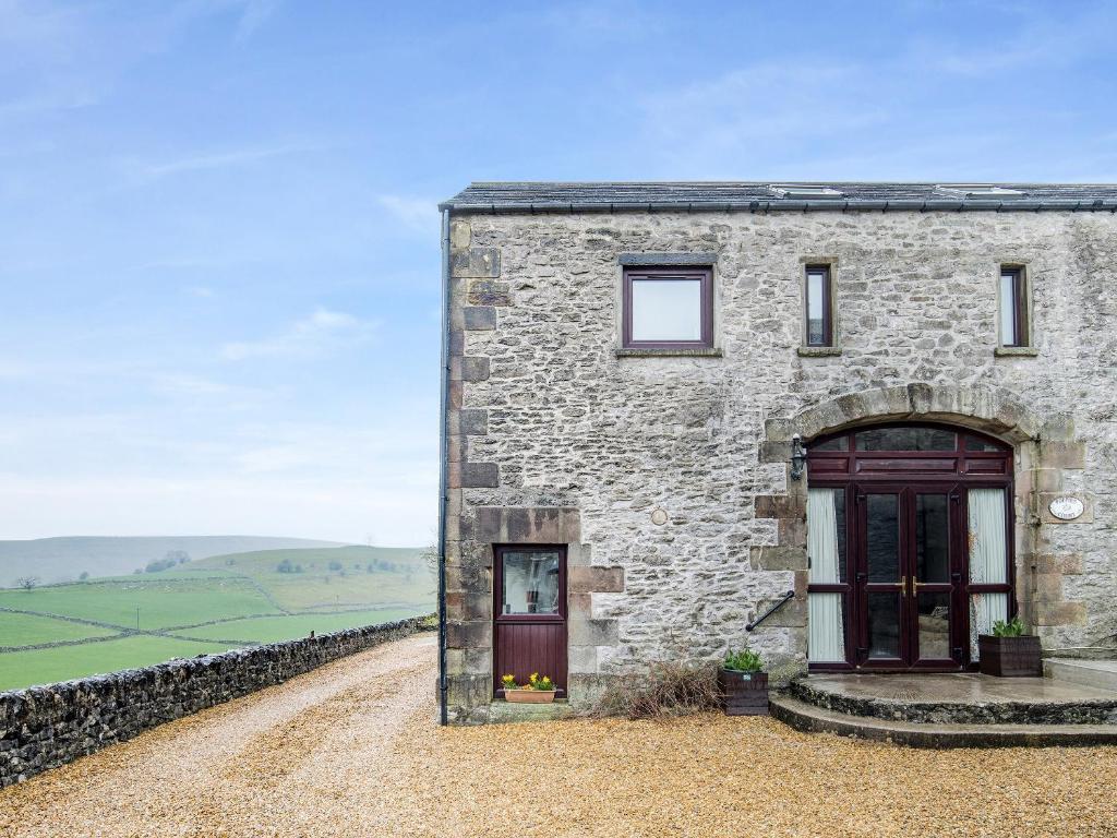 a stone house with a red door on a gravel road at Poppies Court Jericho Farm in Earl Sterndale