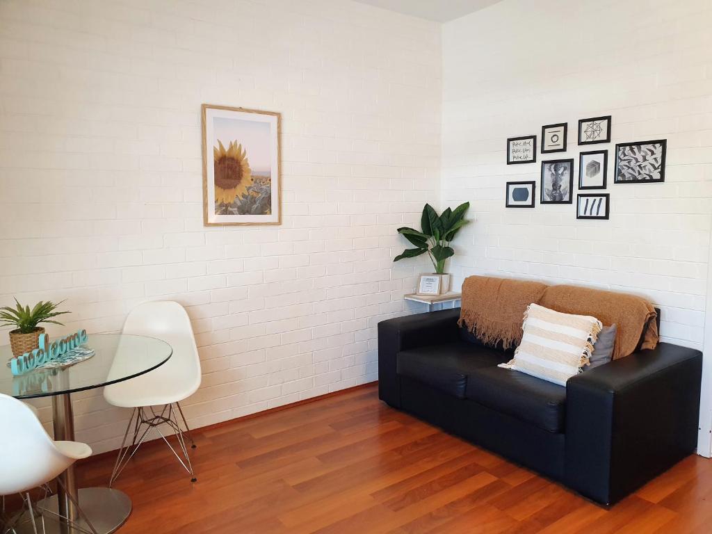 - un salon avec un canapé noir et une table en verre dans l'établissement M106 West Perth Studio Apartment near Kings Park, à Perth