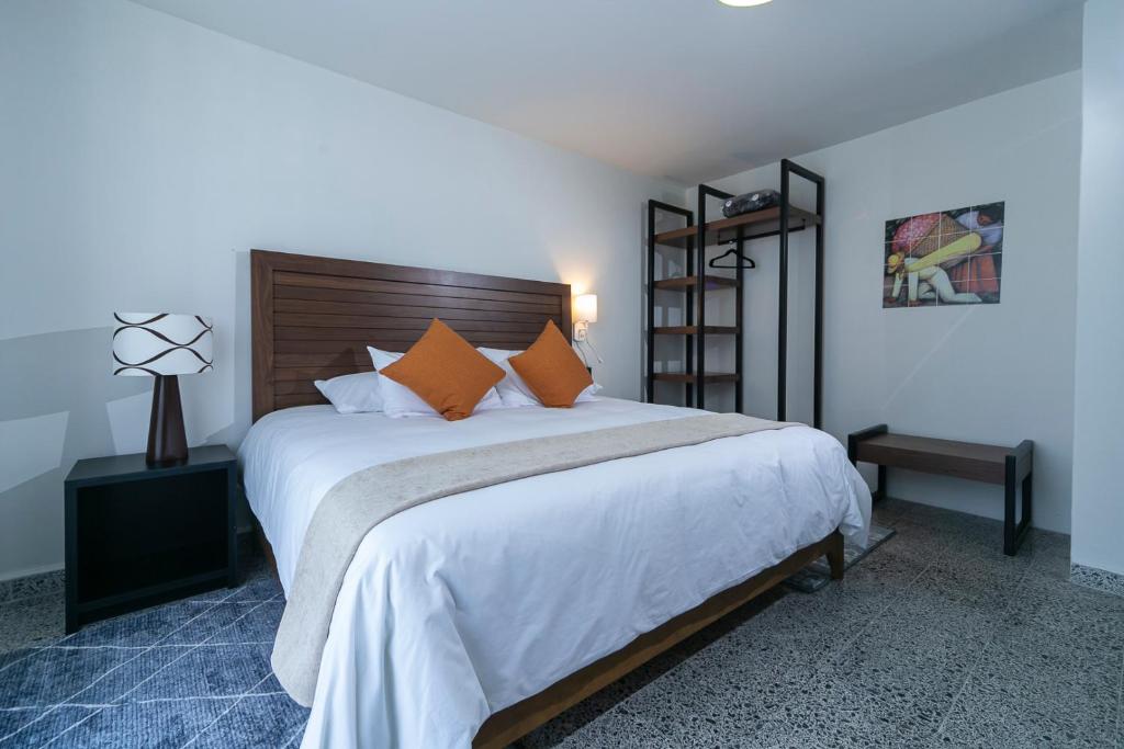 1 dormitorio con 1 cama grande con sábanas blancas y almohadas de color naranja en Casa Sofía Hotel Boutique en Atlacomulco de Fabela