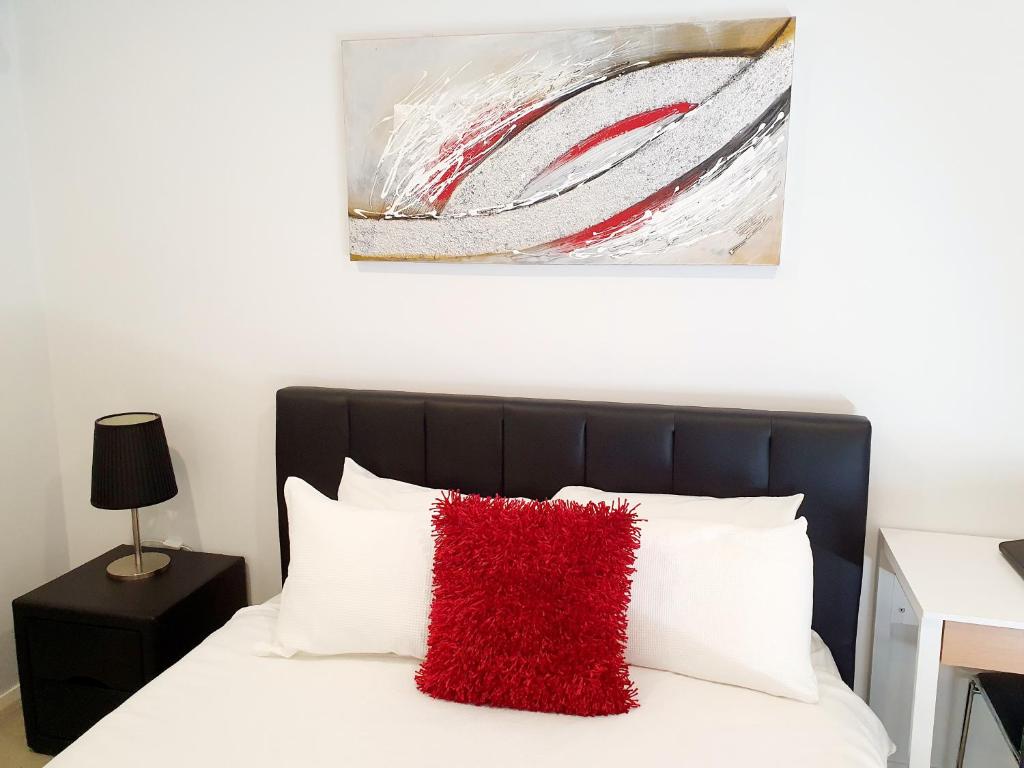 een slaapkamer met een bed met een rood kussen erop bij M5 West Perth Studio Apartment near Kings Park in Perth