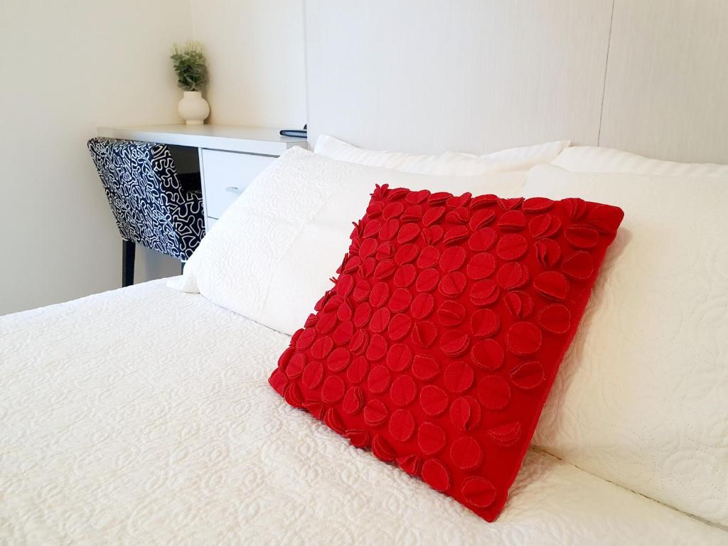 uma almofada vermelha sentada em cima de uma cama em M4 West Perth Studio Apartment near Kings Park em Perth