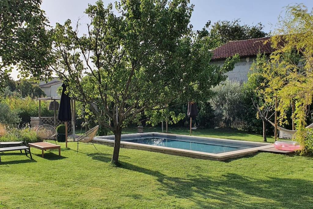 una piscina en un patio con un árbol en Mas provençal, en Sarrians