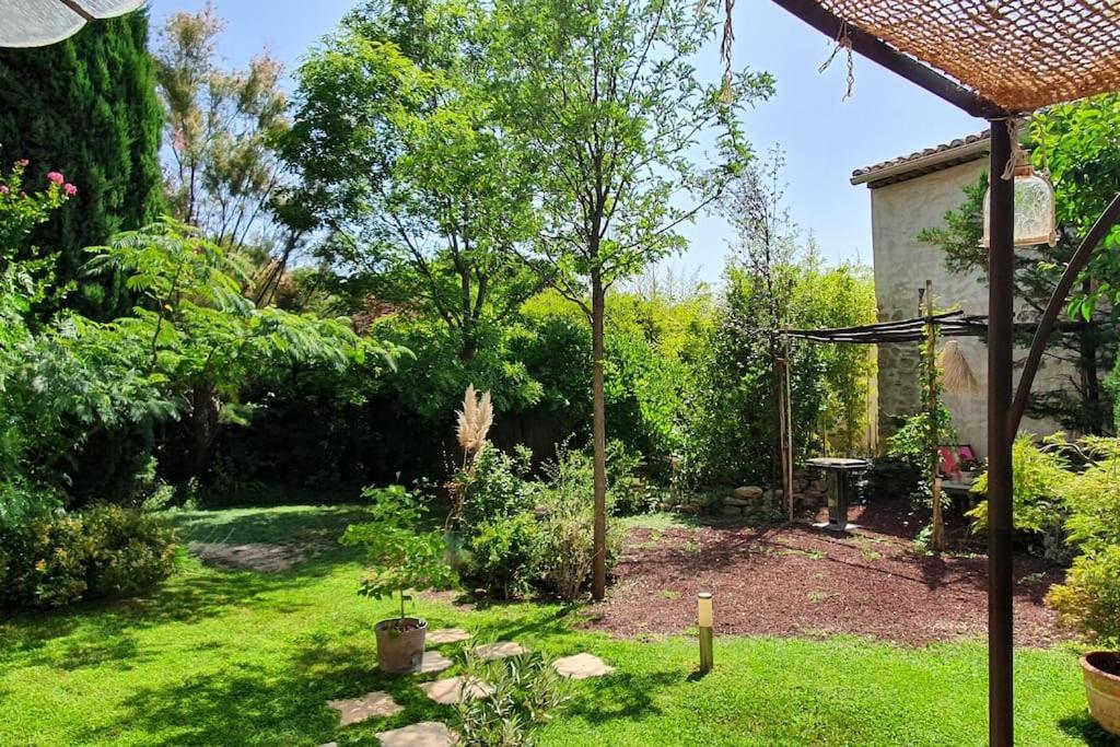 un patio trasero con un jardín con mesa y árboles en Mas provençal, en Sarrians