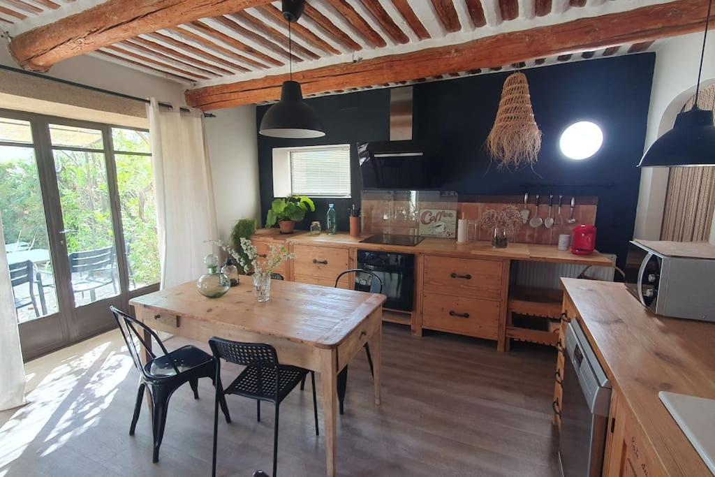 una cocina con mesa de madera y sillas. en Mas provençal, en Sarrians