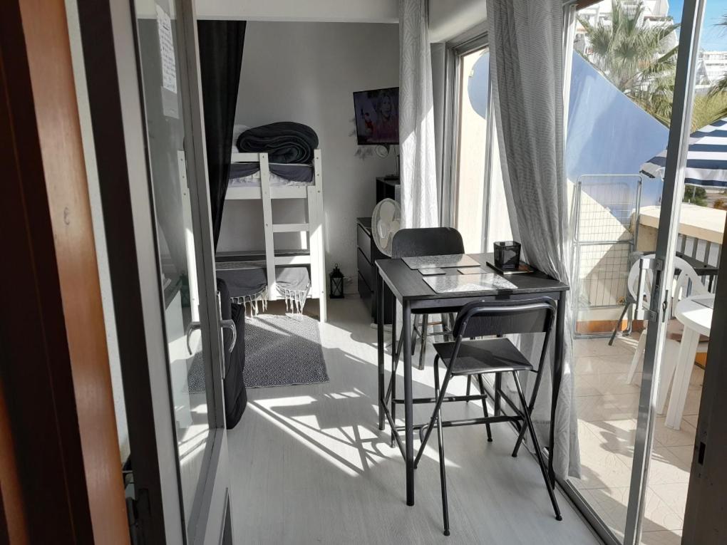 een kleine kamer met een tafel en stoelen en een balkon bij Studio cabine Romy in La Grande-Motte
