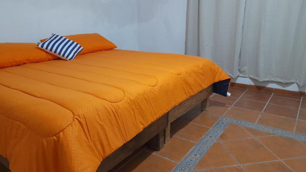 una cama naranja con una almohada encima en Posada El Refugio, en Mineral de Pozos