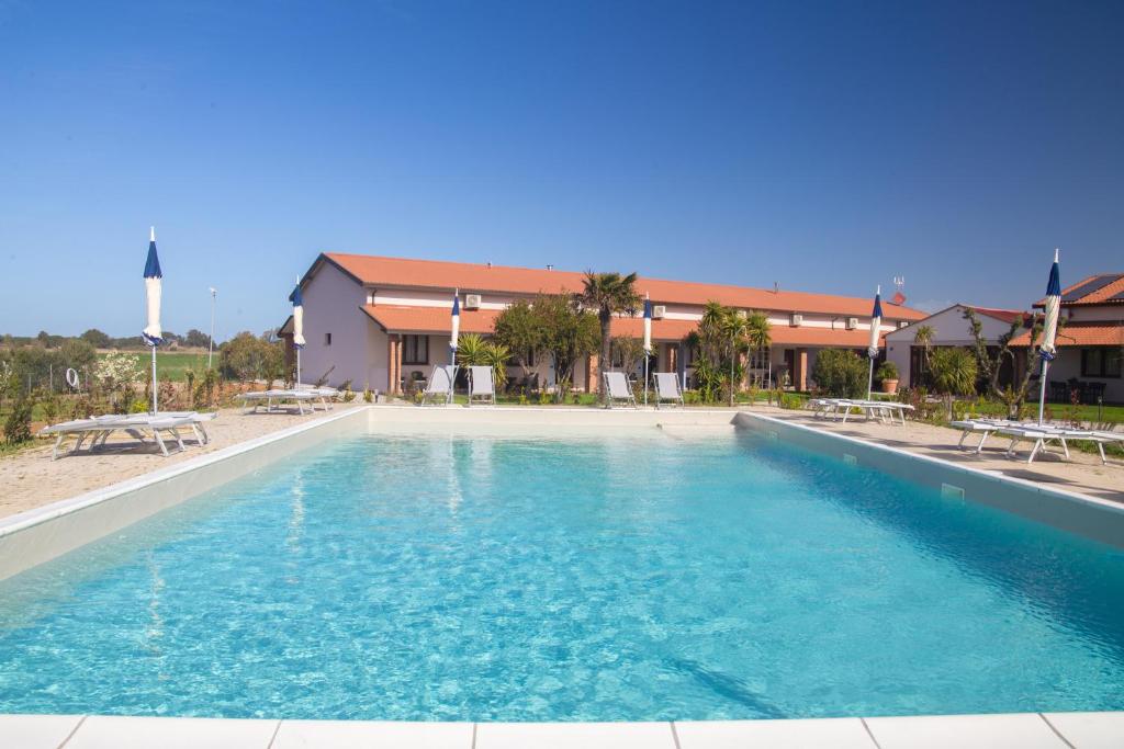 une grande piscine avec des chaises et un bâtiment dans l'établissement Delfino Tuscany Resort, à Marina di Cecina