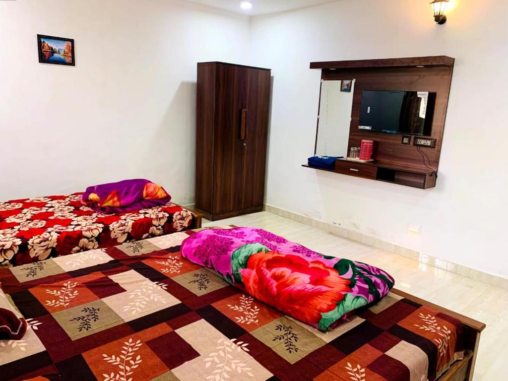 a bedroom with a bed and a tv on a wall at Kalyani Homestay in Kodaikānāl