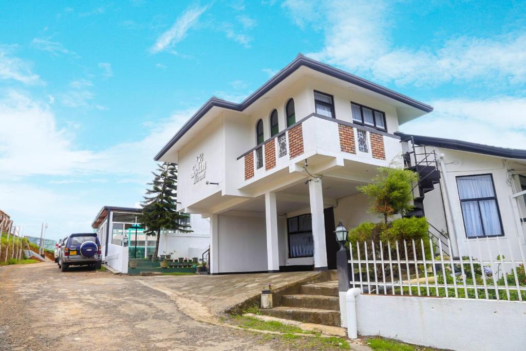 a white house with a car parked in the driveway at Span Grand @ Nuwara Eliya in Nuwara Eliya