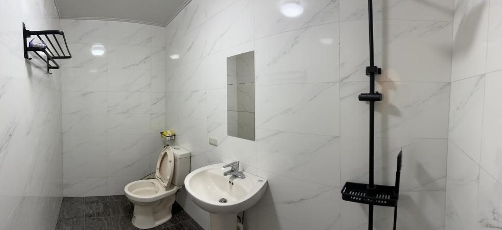a white bathroom with a toilet and a sink at 鰆居Chun House 三仙台 in Chenggong