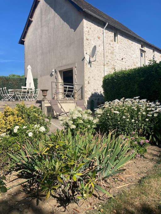 un bâtiment avec une table et des chaises dans un jardin dans l'établissement Maison place champs de foire 6 pers 3 chambres jardin terrasse, à Chamberet