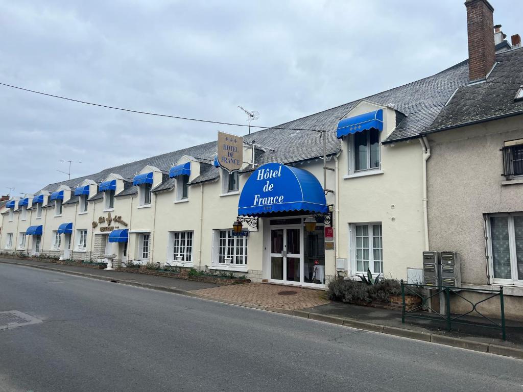 un hôtel d'une maison avec des auvents bleus dans une rue dans l'établissement Contact Hôtel de France Contres-Beauval-Cheverny, à Contres