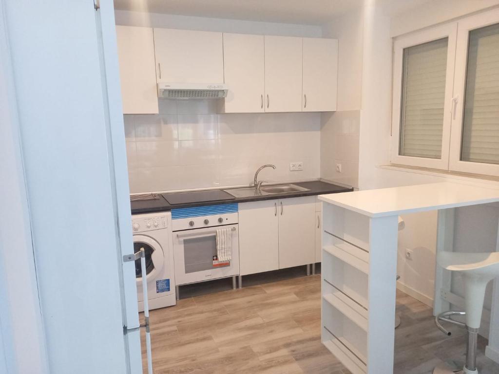 a kitchen with white cabinets and a sink and a stove at APARTAMENTO BAJO ALCOBENDAS in Alcobendas