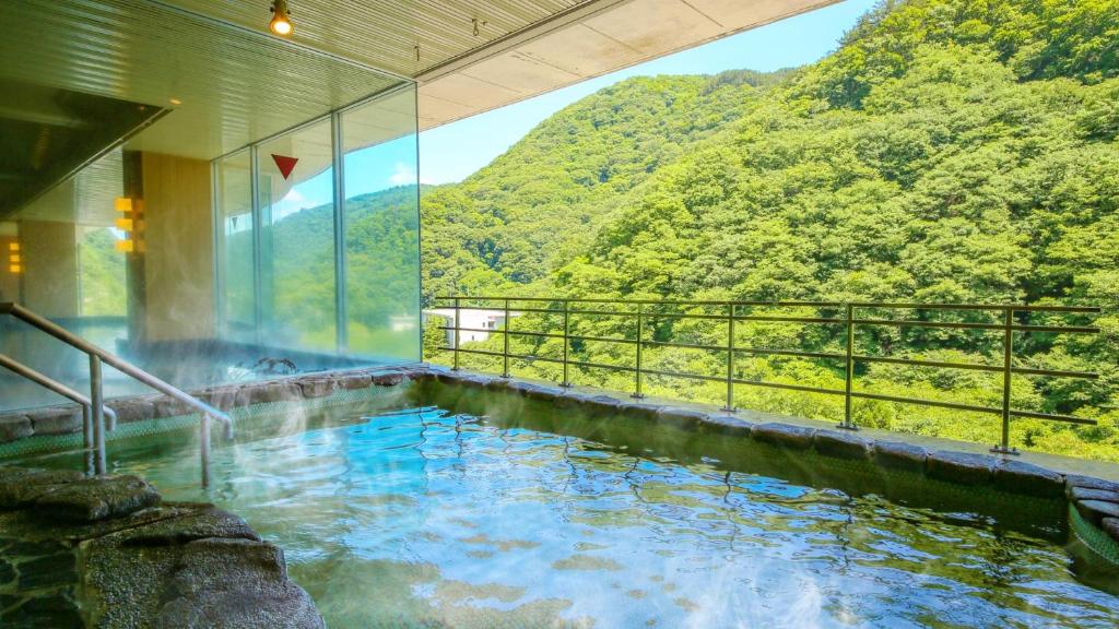 bañera de hidromasaje con vistas a la montaña en Ooedo Onsen Monogatari Higashiyama Grand Hotel, en Aizuwakamatsu