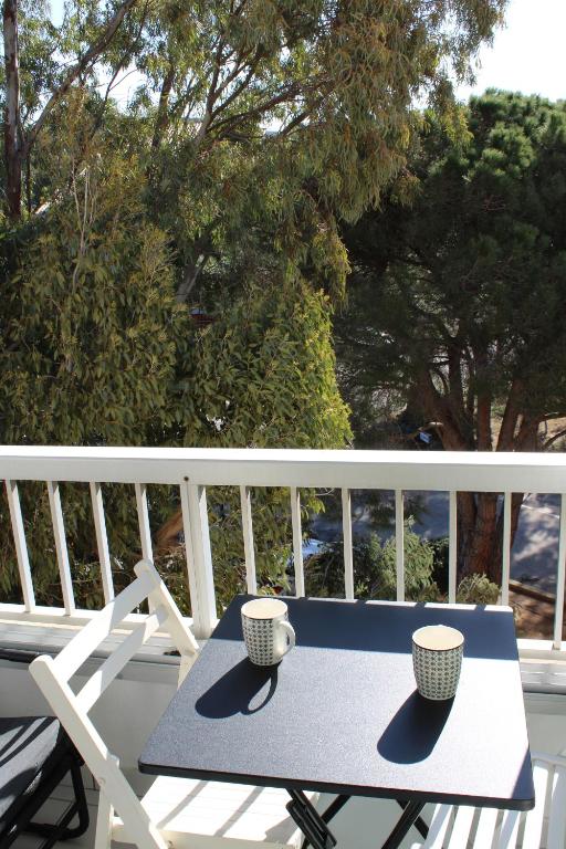 une table bleue avec deux tasses sur un balcon dans l'établissement Studio l'Echappée mandréenne le calme entre mer et forêt, à Saint-Mandrier-sur-Mer