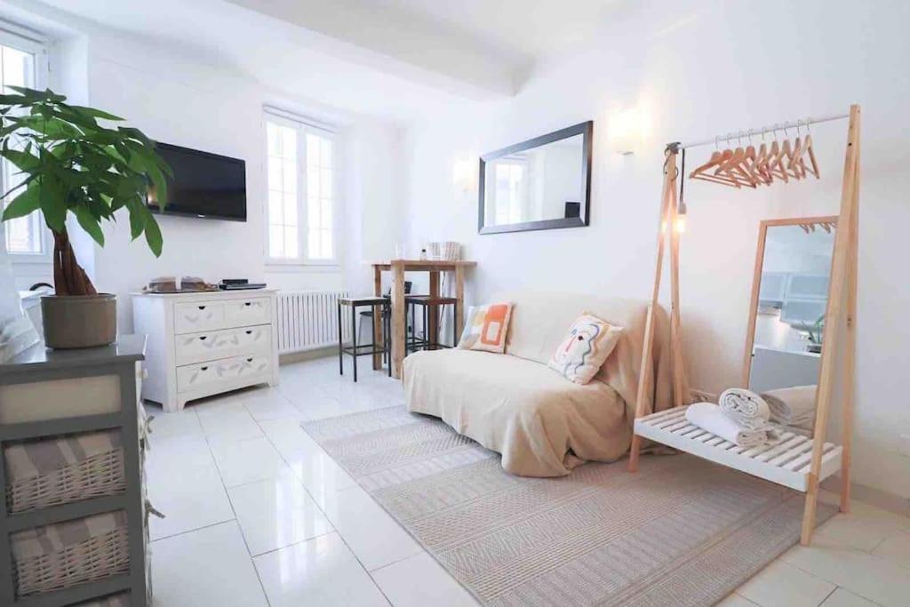 a white room with a bed and a mirror at Cosy studio situé en plein cœur du vieil antibes. in Antibes