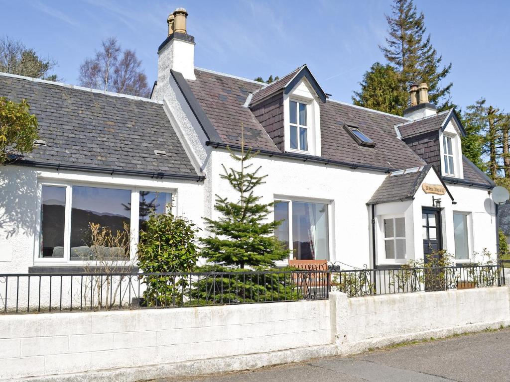 uma casa branca com um telhado preto e uma cerca em Elmbank em Lochcarron