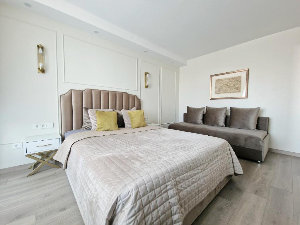 een slaapkamer met een groot bed en een bank bij Vanilės apartamentai in Klaipėda