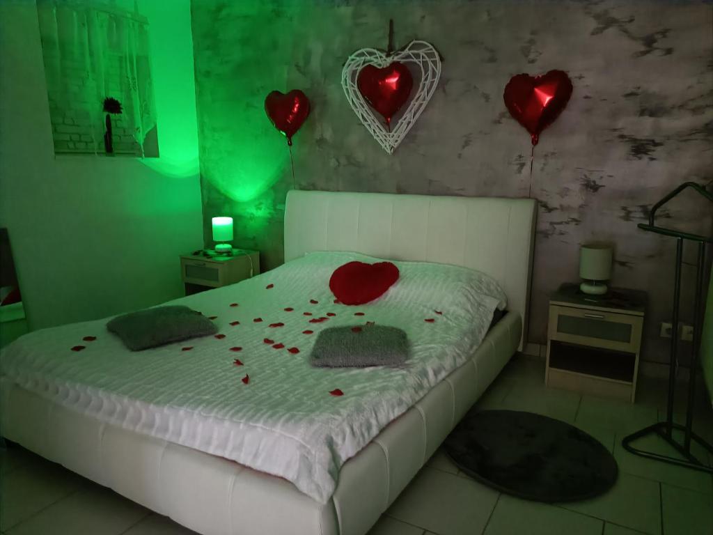 1 dormitorio con 1 cama con corazones rojos en la pared en Virtuel Spa en Achicourt