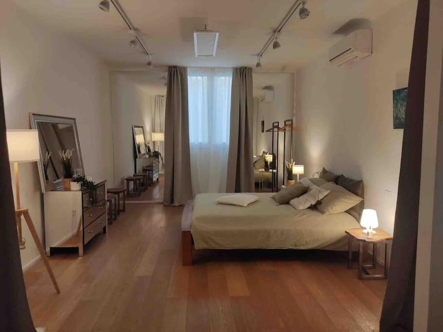 1 dormitorio con 1 cama grande y suelo de madera en Interno4home: In centro storico con posto auto, en Ferrara