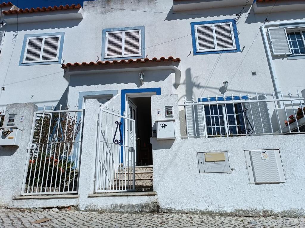a white house with a blue door and gate at Alojamento local Família Coelho in Quinta do Conde