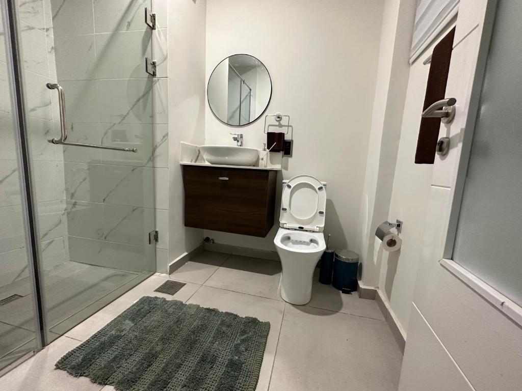 een badkamer met een toilet, een wastafel en een spiegel bij Studio Apartment in Accra