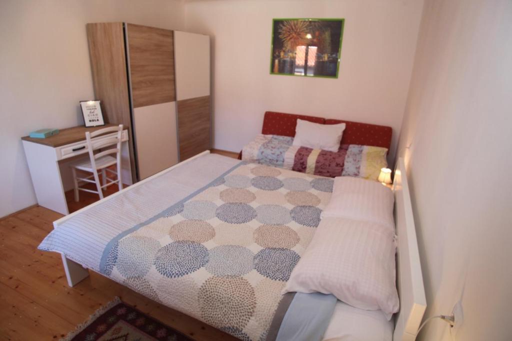 a small bedroom with a bed and a desk at Apartments Anita in Veli Lošinj