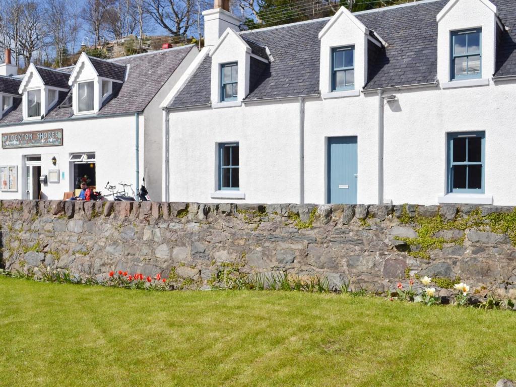 a white house with a stone wall at Bayview Cottage in Plockton