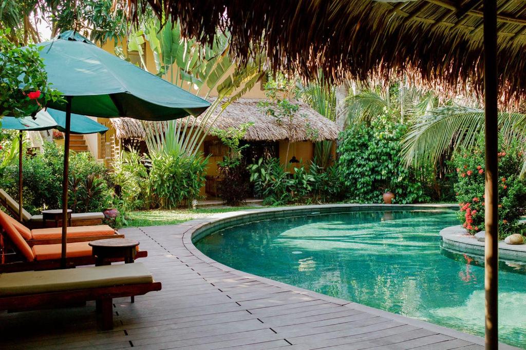 einen Pool mit einem Sonnenschirm, einem Stuhl und einem Tisch in der Unterkunft An Villa boutique resort in Hoi An