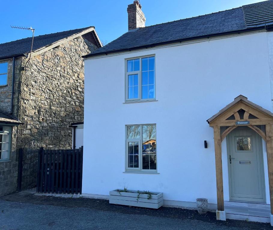 una casa bianca con una porta bianca e un edificio in mattoni di Trevose a Wrexham