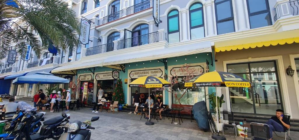 un grupo de personas sentadas fuera de un edificio con sombrillas en BREAKING DAWN- TAEYANG Hotel Phú Quốc en Phu Quoc