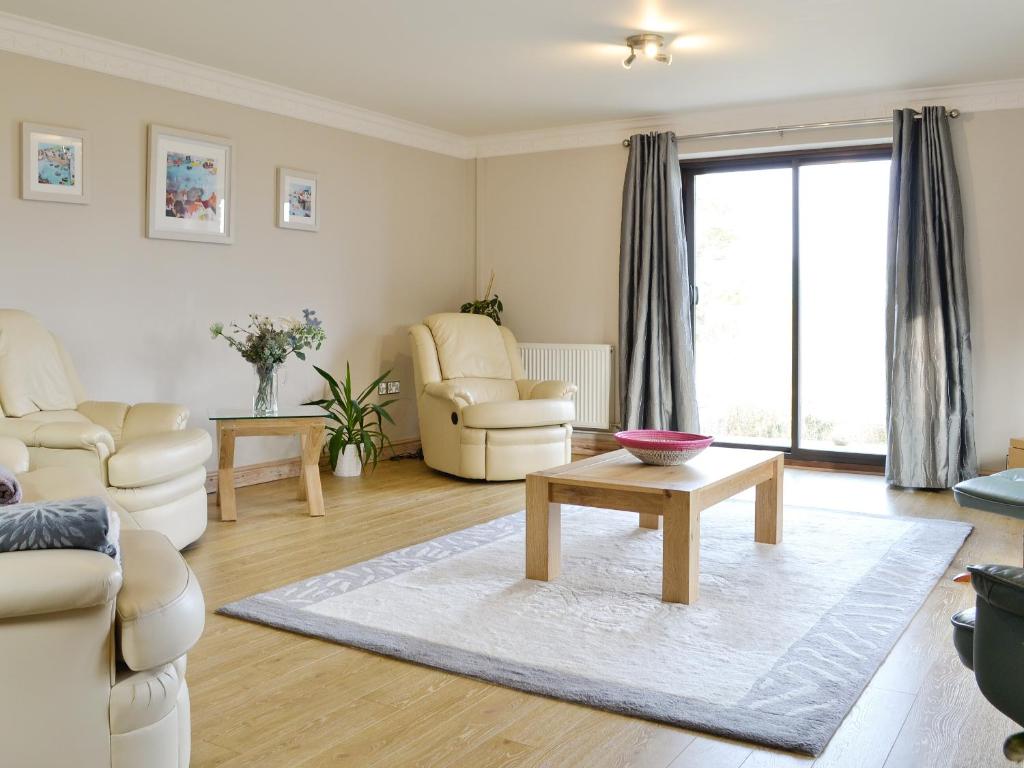 a living room with white furniture and a coffee table at Llety-R-Wennol in Llangain