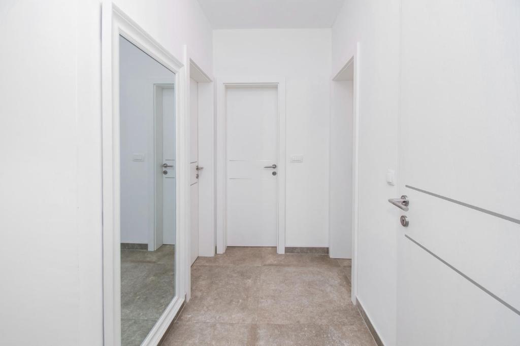 - un couloir blanc avec deux placards et un miroir dans l'établissement Apartman Benmi, à Vodice